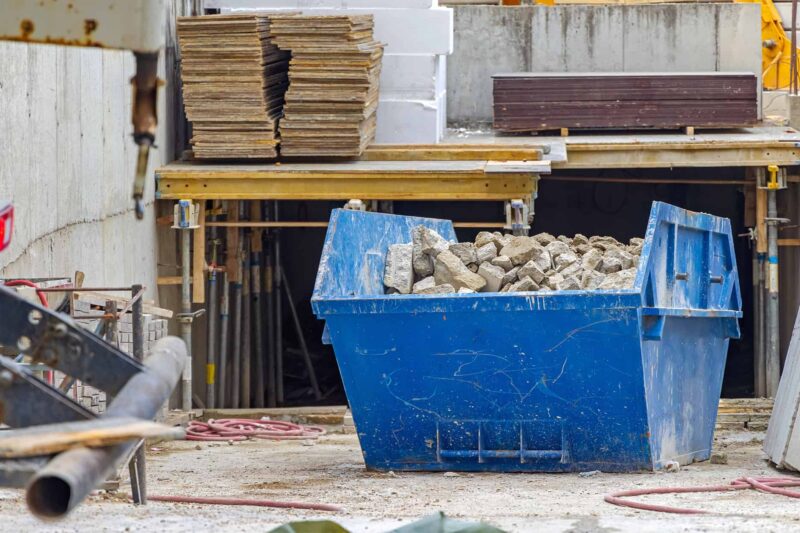 Front-view-of-a-container-full-of-construction-debris-at-a-construction-site Front-view-of-a-container-full-of-construction-debris-at-a-construction-site